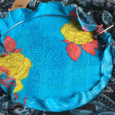 A circular applique world in turquoise with little hand stitches.